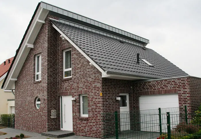 Referenz Hausbau: Modernes Einfamilienhaus mit dunklem Ziegelfassaden und Garage.