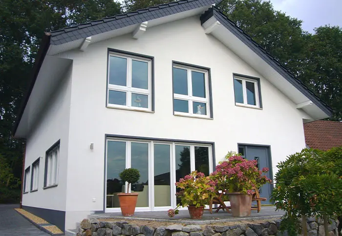 Referenz Hausbau: Fassade eines modernen, weißen Einfamilienhauses mit grauen Fensterrahmen und Schiebetür
