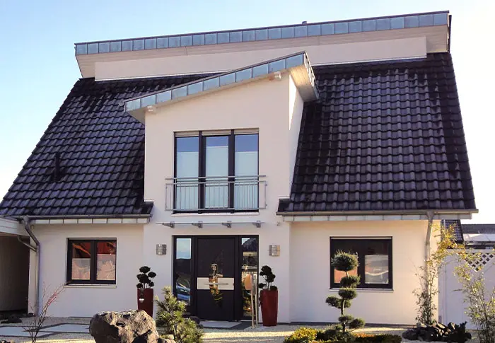 Referenz Hausbau: Modernes, zweistöckiges Haus mit dunklem Ziegeldach und hellem Fassadenputz