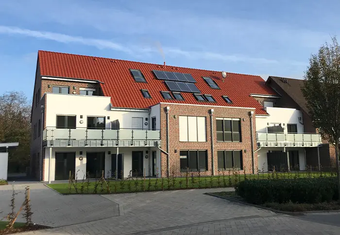 Ansicht eines modernen Mehrfamilienhauses mit roten Ziegeln und Balkonen, Wohnungsbau.