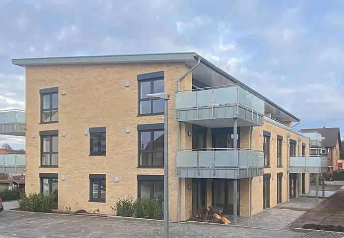 Middendorf-Bau GmbH Referenz: Mehrfamilienhaus mit gelber Fassade und Balkonen.