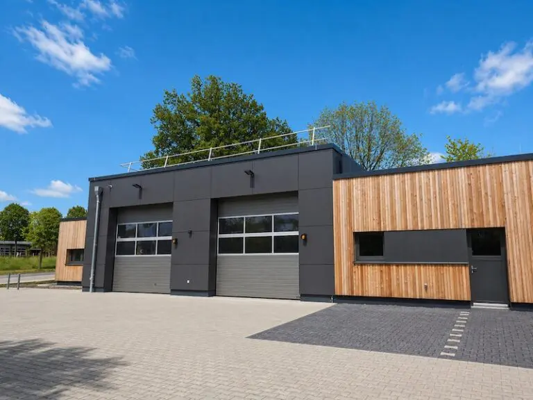 Modernes Rettungsstellengebäude mit zwei Garagentoren und Holzfassade unter blauem Himmel