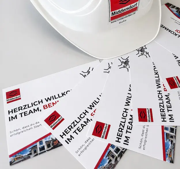 Weißer Bauhelm der Firma Middendorf auf mehreren Willkommenskarten für neue Mitarbeiter