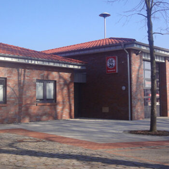 Außenansicht eines Backsteingebäudes mit roten Ziegeln, vermutlich ein Feuerwehrhaus.