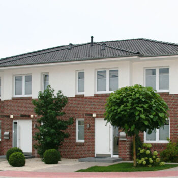 Referenz Hausbau: Fassade eines modernen Doppelhauses mit Klinker und weißen Elementen, graues Dach.