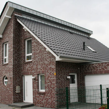 Referenz Hausbau: Modernes Einfamilienhaus mit dunklem Ziegelfassaden und Garage.