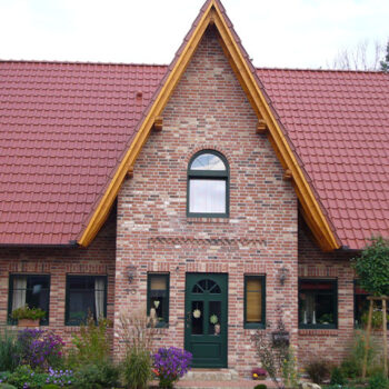Ansicht eines Einfamilienhauses im Landhausstil mit rotem Ziegeldach und Fassade aus roten Backsteinen.