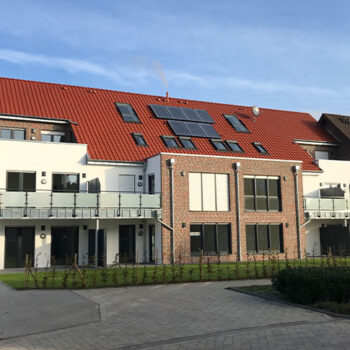 Ansicht eines modernen Mehrfamilienhauses mit roten Ziegeln und Balkonen, Wohnungsbau.