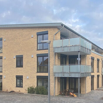 Middendorf-Bau GmbH Referenz: Mehrfamilienhaus mit gelber Fassade und Balkonen.