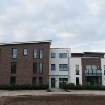 Referenz Wohnungsbau: Mehrfamilienhaus mit Fassade aus Backstein und weißem Putz.