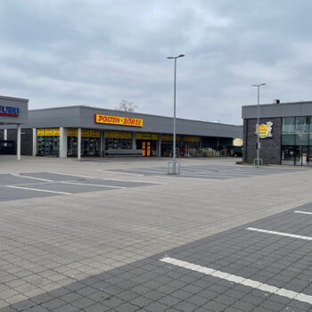 Gewerbebau: Ansicht von Aldi, Posten Börse und Bäckerei mit Parkplätzen vor den Gebäuden.